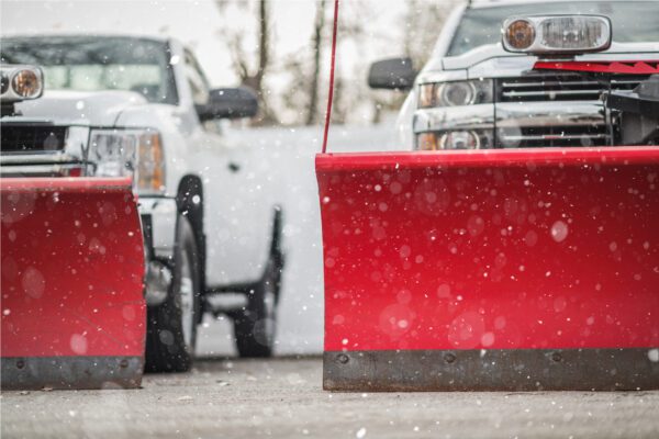 Adjustable Commercial Grade Plow Blades Installed on a Pickup Trucks. Vehicles Ready For a First Snow Fall. Falling Snow.